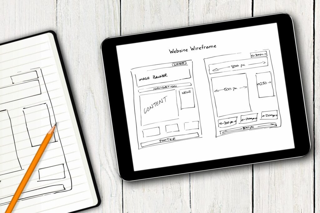 A notebook and digital tablet with sketches of a website design